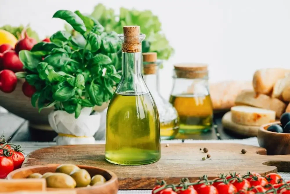 a bottle of olive oil takes center stage amongst various vegetables