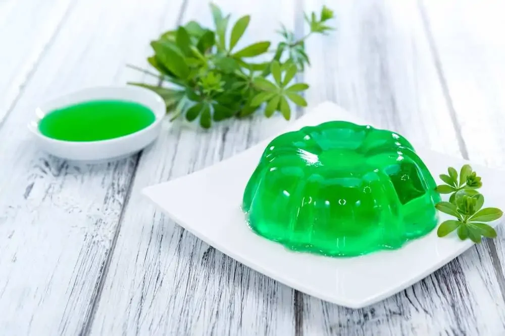 green jello pudding, vegan friendly, on a white plate placed on a white oak table