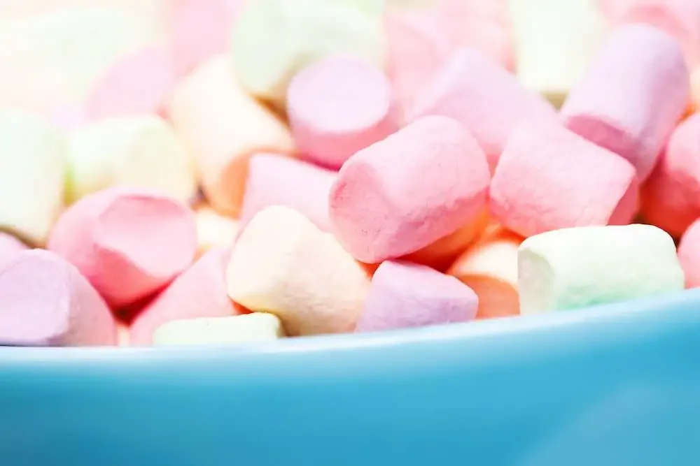 blue bowl full of pink and yellow plant-based marshmallows