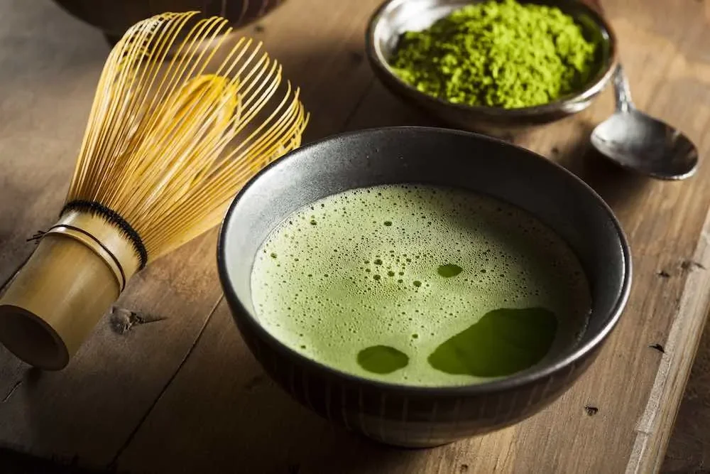 matcha green tea in a bowl with brewing brush